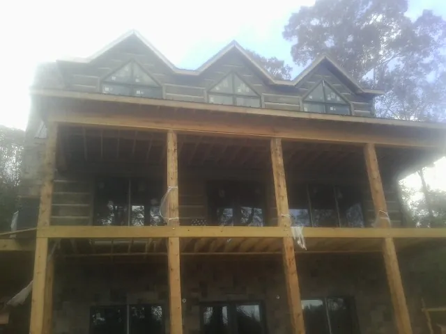 Dormers and porch framing on a large log home under construction — Roof Coating work by our crew in Buffalo